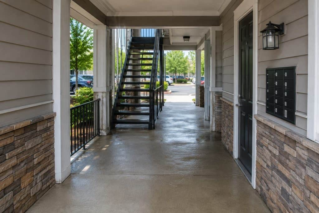Clean apartment breezeway with concrete floors, stairways, railings, exterior walls, doors, and shared entry areas in Raleigh and Cary.