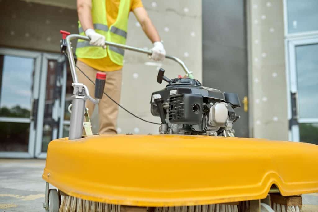 Professional technician performing dumpster pad power washing at a commercial property